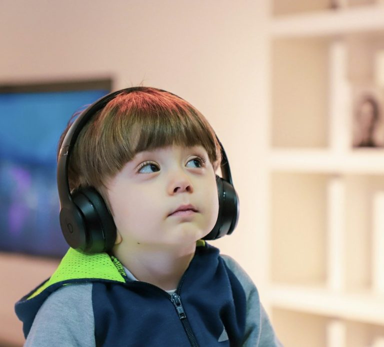 Young child wearing headphones, looking upwards with a thoughtful expression.