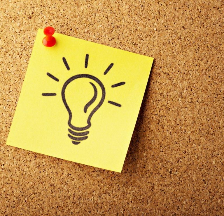 Yellow sticky note with a light bulb illustration pinned to a corkboard.