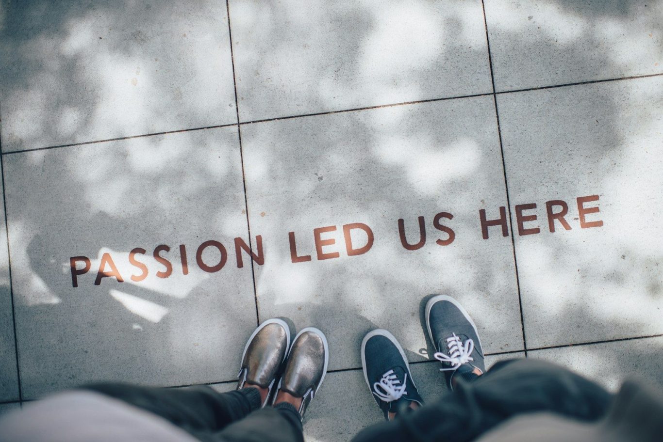 Text on the ground reads "PASSION LED US HERE" with two pairs of shoes in view.